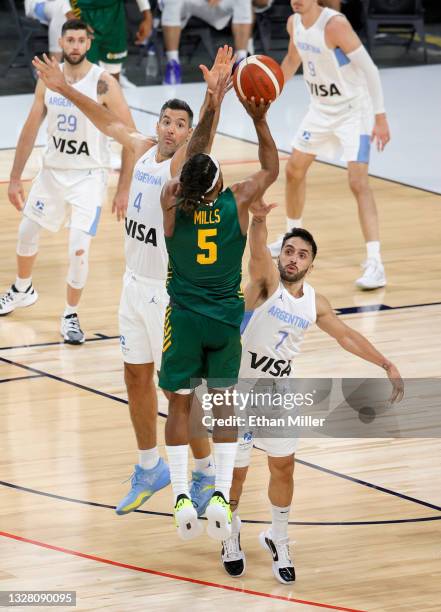 Patty Mills of the Australia Boomers hits a 3-pointer against Luis Scola and Facundo Campazzo of Argentina at the end of regulation of their...