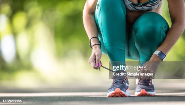 detail of a woman fastening her shoelaces on trainers befure running. - tied up stock pictures, royalty-free photos & images