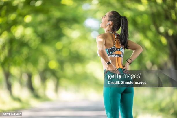sporting woman with tapes on her back holds her low back with an expression of pain on her face. - lower bildbanksfoton och bilder