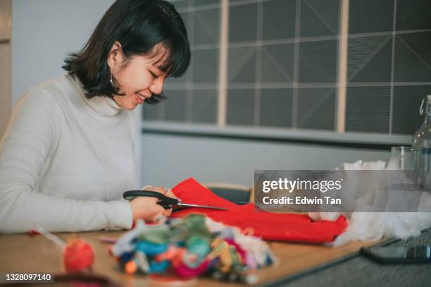 asian chinese teenage girl cutting fabric preparing cross-stitch craft at home side hustle - felt textile stock pictures, royalty-free photos & images