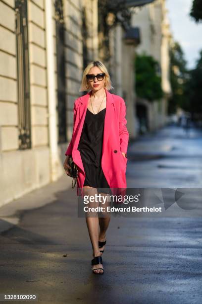 Emy Venturini wears black sunglasses, from Dita Eyewear, a gold chain pendant, a black V-neck dress / sleep dress from Miu Miu, a pink fuchsia...