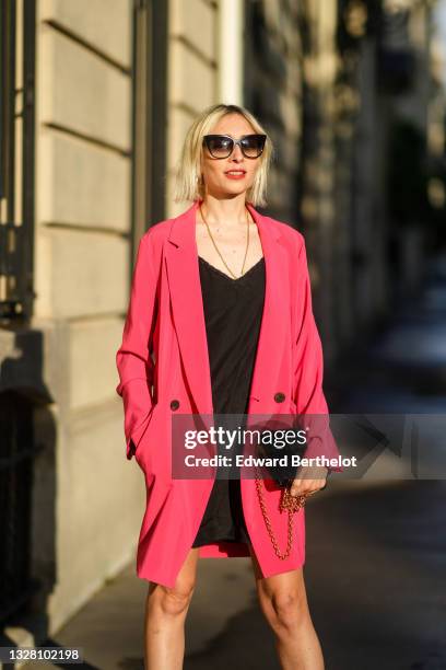 Emy Venturini wears black sunglasses, from Dita Eyewear, a gold chain pendant, a black V-neck dress / sleep dress from Miu Miu, a pink fuchsia...