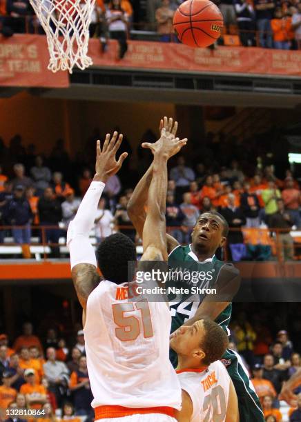 George Beamon of the Manhattan College Jaspers shoots the ball against Fab Melo and Brandon Triche of the Syracuse Orange during the NIT Season...
