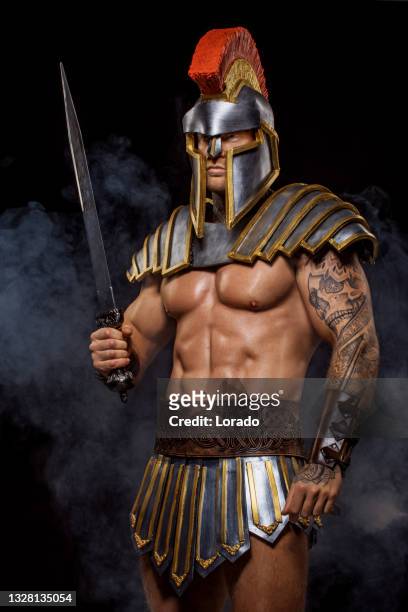 un apuesto y musculoso gladiador guerrero sosteniendo un arma - sword fotografías e imágenes de stock