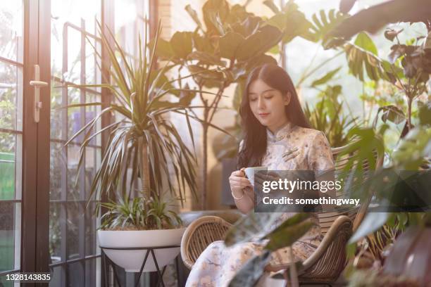 eine frau trinkt kaffee auf dem balkon - the cheongsam stock-fotos und bilder