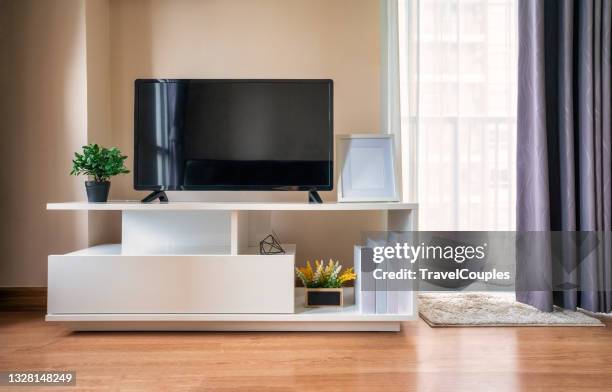 smart tv on the cabinet in modern living room on white wall background. modern white shelf with flat tv at home - chaîne de télévision photos et images de collection