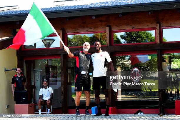 Head Coach of AC Milan Stefano Pioli and Fikayo Tomori wave the Italian flag during the AC Milan training session at Milanello on July 11, 2021 in...