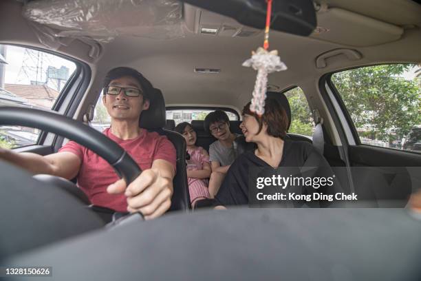 pais chineses asiáticos e seus filhos curtindo enquanto viajam de carro. a vista é através do para-brisa. - family inside car - fotografias e filmes do acervo