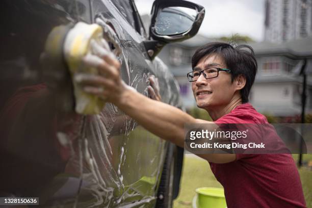 asian chinese mid adult man washing car at his backyard - chinese car home stockfoto's en -beelden