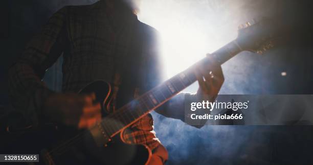 rock guitarist playing guitar in a live show with stage lights - indie rock stock pictures, royalty-free photos & images