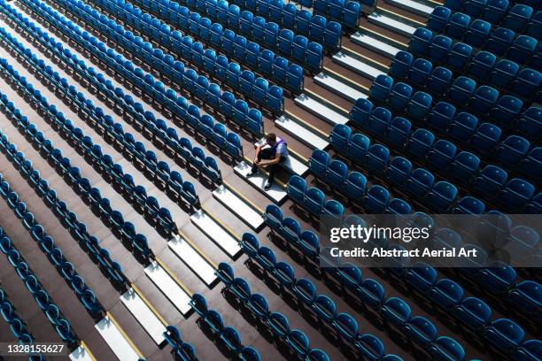 high angle view showing a person sitting amongst empty stadium seating, united kingdom - stadium seats stock pictures, royalty-free photos & images