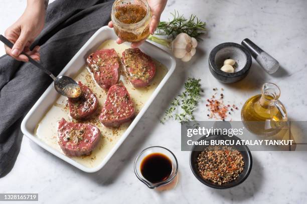 woman marinating meat with herbs and seasonings - garlic sauce stock pictures, royalty-free photos & images