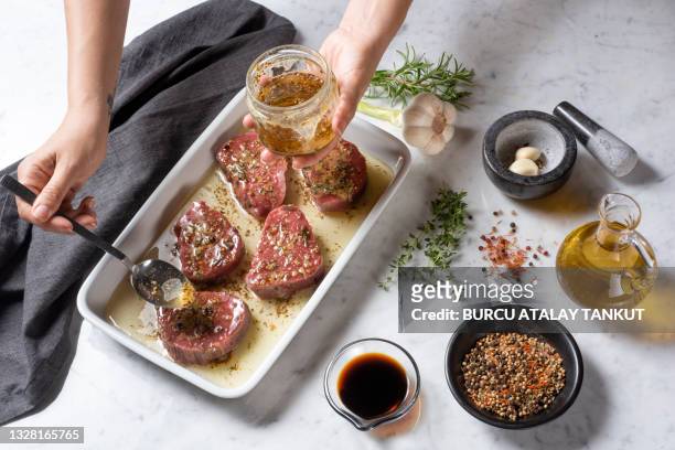 woman marinating meat with herbs and seasonings - marinated stock pictures, royalty-free photos & images