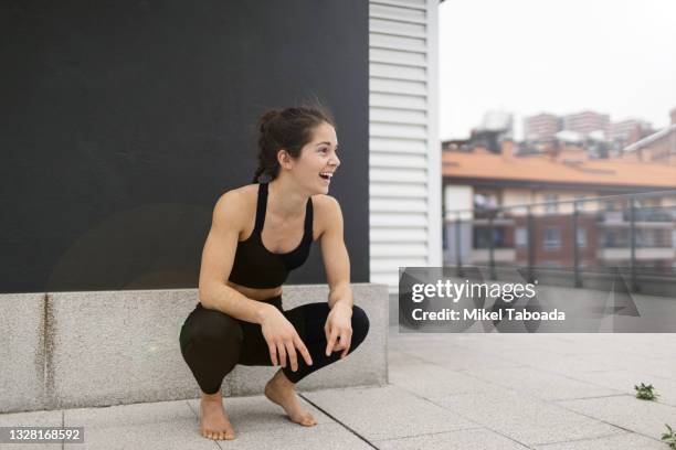 young woman laughing while is crouched down - agachar se imagens e fotografias de stock