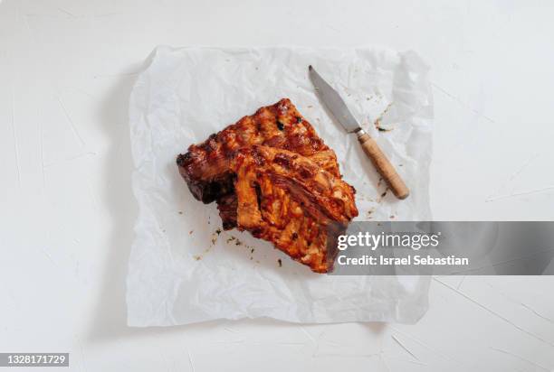 top view of delicious charcoal grilled ribs cut on a baking paper and white background. ideal food to celebrate labor day. - gegrilltes schweinefleisch stock-fotos und bilder