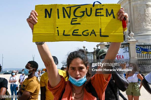 An immigrant hoists a "Nobody is Illegal" placard at the demonstration in Praça do Comercio to protest against current practices by SEF related to...