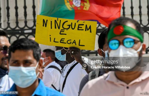 Mask-clad immigrant hoists a "Nobody is Illegal" placard at the demonstration in Praça do Comercio to protest against current practices by SEF...