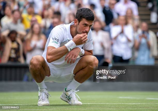 Novak Djokovic of Serbia celebrates winning his men's Singles Final match against Matteo Berrettini of Italy by picking grass from the court on Day...