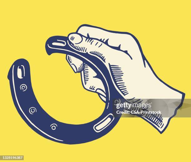 hand holding a horseshoe - horseshoe stock illustrations