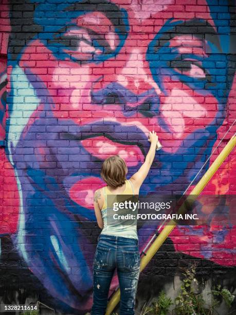 young woman painting mural on the house - girl power graffitti stock pictures, royalty-free photos & images