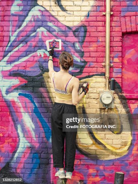 young woman painting mural on the house - graffiti mural stock pictures, royalty-free photos & images