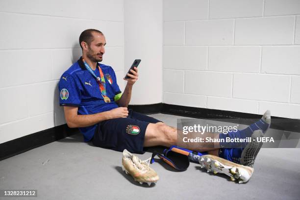 Giorgio Chiellini of Italy wears his winners medal as he uses his phone in the tunnel following his team's victory in the UEFA Euro 2020 Championship...