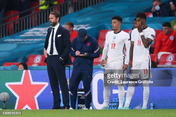 Jadon Sancho and Marcus Rashford of England wait to be substituted on next to Gareth Southgate, Head Coach of England during the UEFA Euro 2020...