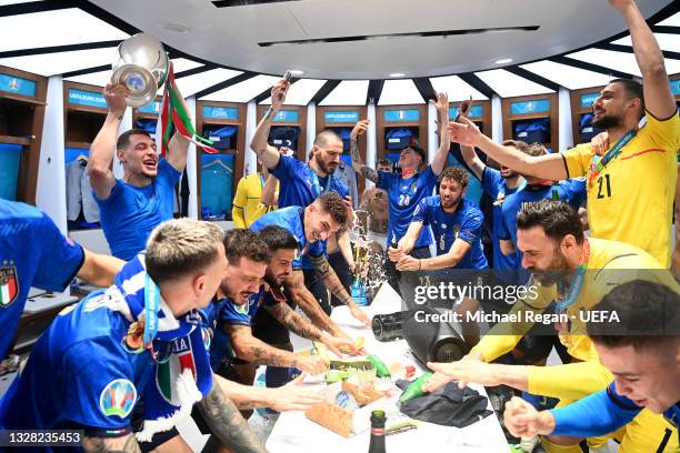 Andrea Belotti of Italy celebrates with team mates as he holds The Henri Delaunay Trophy inside the dressing room following their team's victory in...