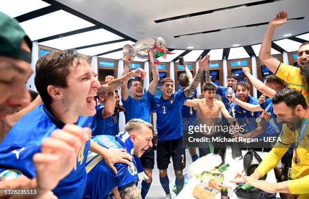 Andrea Belotti of Italy celebrates with team mates as he holds The Henri Delaunay Trophy inside the dressing room following their team's victory in...