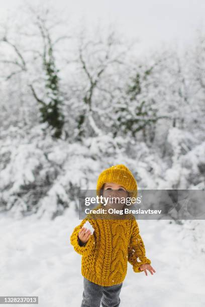 cute baby girl in knitted winter hat and sweater outside in winter forest - baby lachen natur stock-fotos und bilder