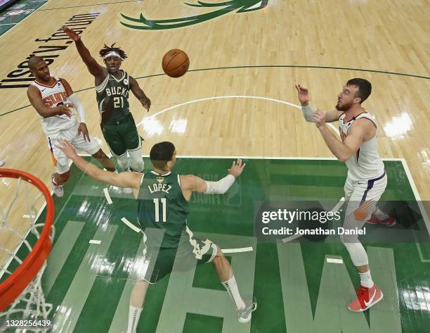 Chris Paul of the Phoenix Suns passes to Frank Kaminsky around Brook Lopez of the Milwaukee Bucks at Fiserv Forum on July 11, 2021 in Milwaukee,...