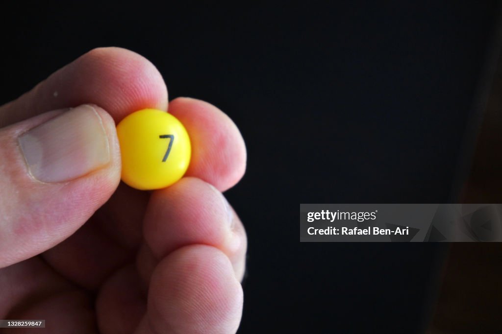 Person holding a small ball with the number 7 seven