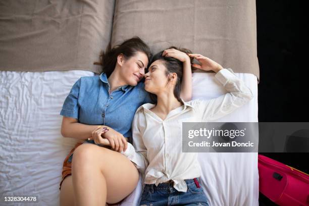 two teenage lesbian girls cuddling in bed - lesbian bed stock pictures, royalty-free photos & images