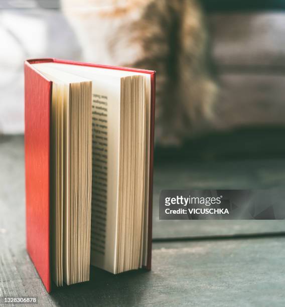opened red book on rustic wooden floor with blurred interior background - hardcover book imagens e fotografias de stock