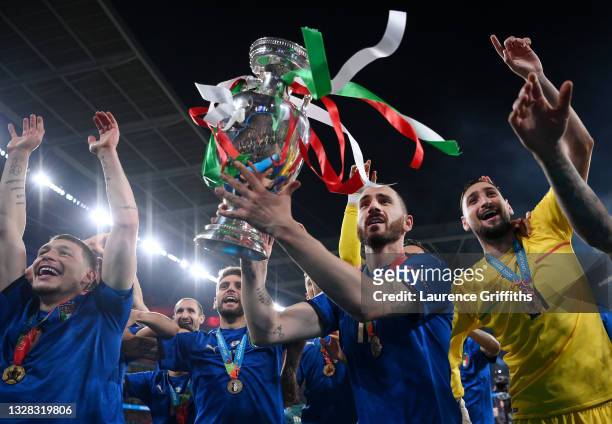 Leonardo Bonucci of Italy celebrates with the European Championship Trophy alongside Andrea Belotti and Gianluigi Donnarumma during the UEFA Euro...