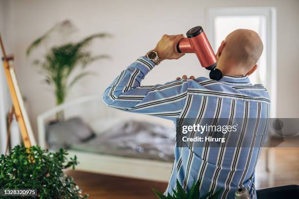 man using massager for his neck - neckache stock pictures, royalty-free photos & images