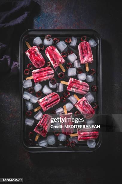 cherry fruit popsicles homemade with yogurt ice cream on ice in moody dark - black cherries stock pictures, royalty-free photos & images