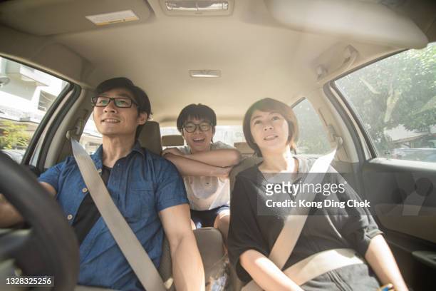 asian chinese parents and their son enjoying while traveling by car. the view is through windshield. - teenage boy looking out window stock pictures, royalty-free photos & images
