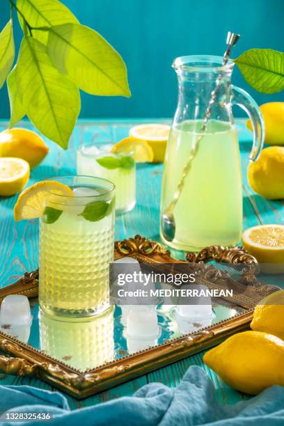 lemonade jar with two glasses and ice cubes refreshing summer on turquoise background - jug stockfoto's en -beelden