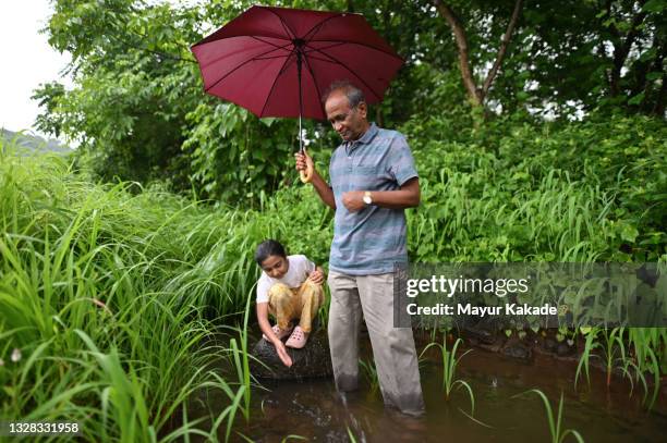 grandfather and granddaughter playing together in a small water stream while it’s raining - rainy season stock pictures, royalty-free photos & images
