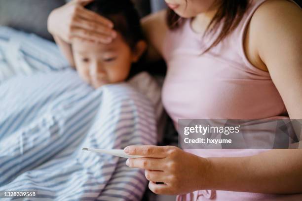 mother measuring body temperature of her daughter - 104 thermometer stock pictures, royalty-free photos & images