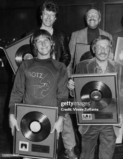 Canadian guitarist Alex Lifeson of progressive rock band Rush holding a platinum disc for the group's album 'All the World's a Stage', USA, circa...