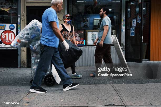 People walk along a street where a 13-year-old boy was killed yesterday in the Bronx on July 12, 2021 in New York City. The shooting, which police...