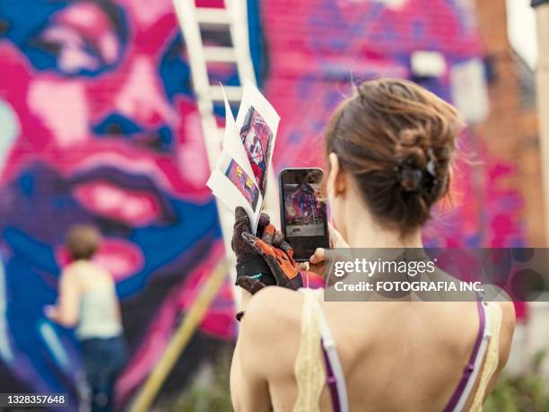 young woman painting mural on the house - photographing graffiti stock pictures, royalty-free photos & images