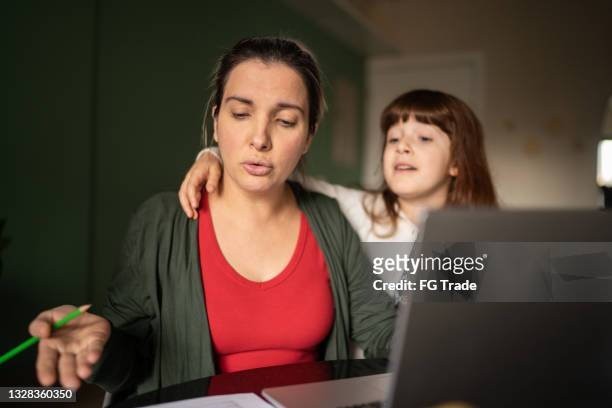 mid adult woman trying to work with daughter at home - busy schedule stock pictures, royalty-free photos & images