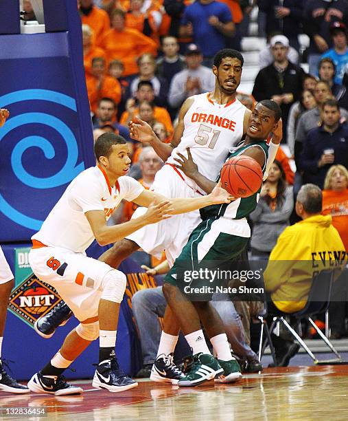 Michael Carter-Williams of the Syracuse Orange reaches for the rebound from teammate Fab Melo as he is blocked by Donovan Kates of the Manhattan...