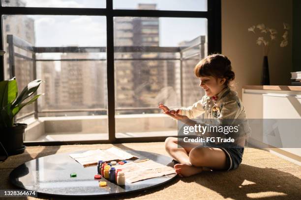 cute girl looking at her hands full of paint at home - sitting on ground stock pictures, royalty-free photos & images