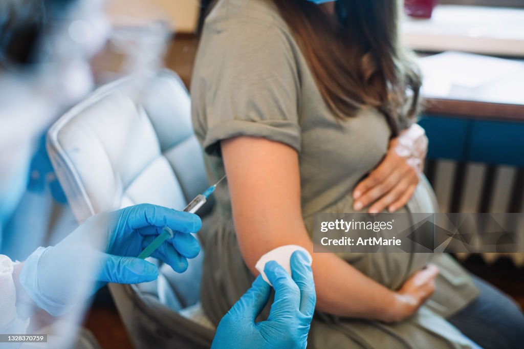 Arzt/Krankenschwester, der schwangeren Frauen eine Impfinjektion verabreicht