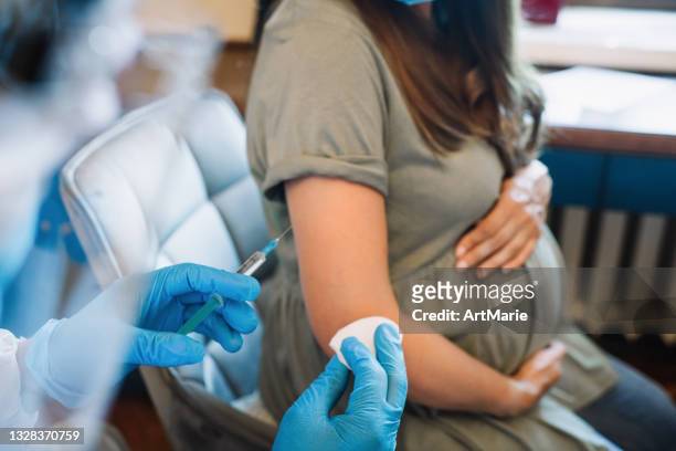 arzt/krankenschwester, der schwangeren frauen eine impfinjektion verabreicht - covid 19 vaccine stock-fotos und bilder