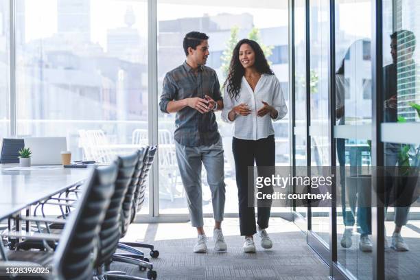 businessman and businesswoman walking and talking - businesswear stock pictures, royalty-free photos & images